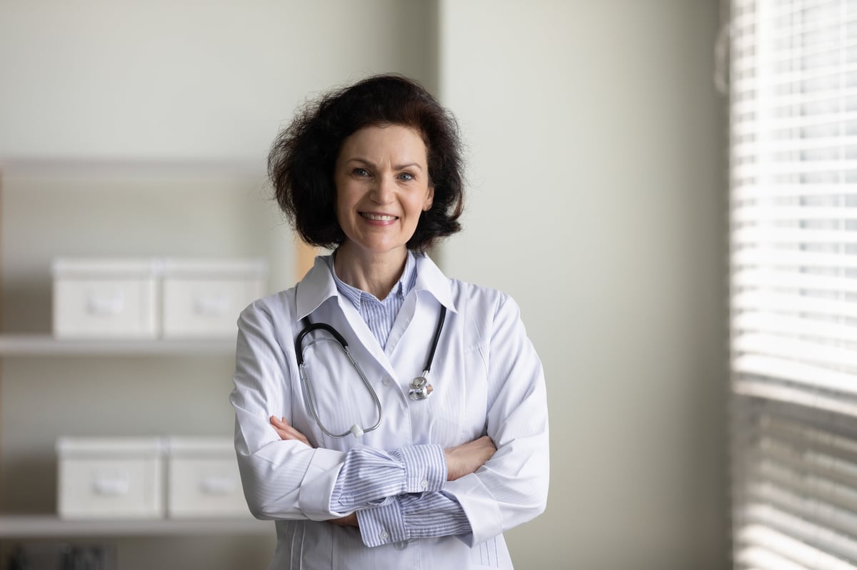 Confident happy mature chief doctor woman in white coat